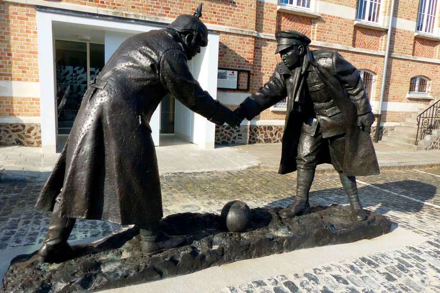 Statua di un soldato tedesco e uno britannico che si stringono la mano su un pallone da calcio