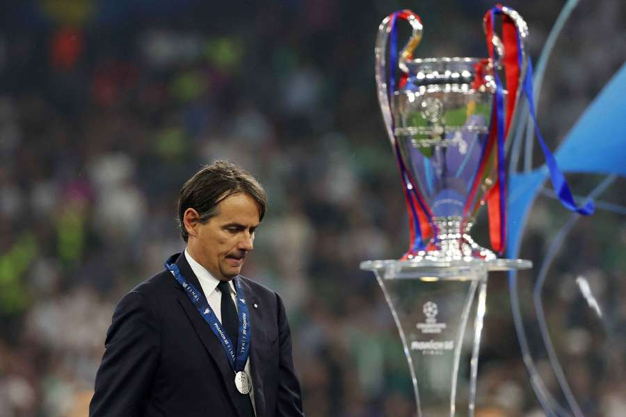 Simone Inzaghi looks dejected as he walks past the Champions League trophy after a historic defeat to PSG