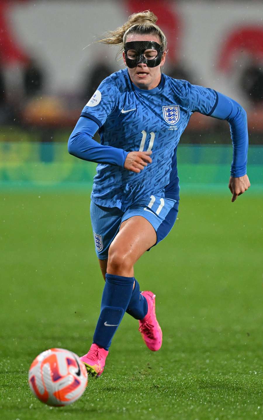 England's striker Lauren Hemp, wearing a protective face mask, runs with the ball during the International football friendly match between England and Australia at the Gtech Community Stadium in Brentford, west London on April 11, 2023