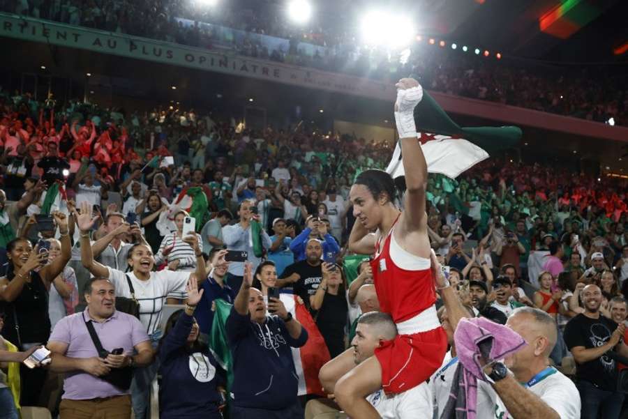 Imane Khelif of Algeria holds an Algerian flag as she celebrates winning against Liu Yang of China