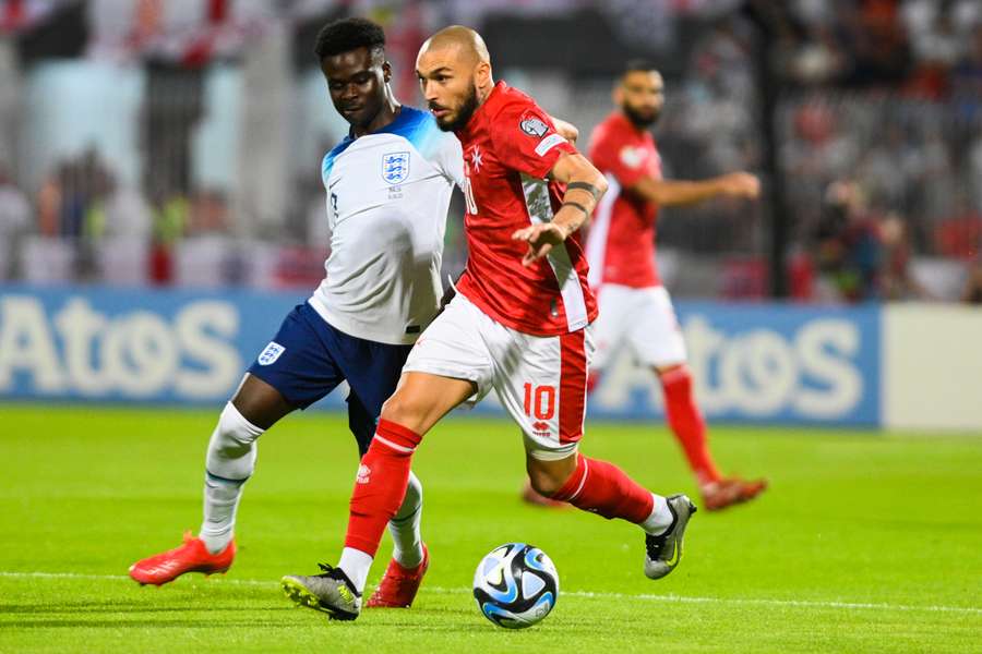 Malta midfielder Teddy Teuma (R) challenges England forward Bukayo Saka