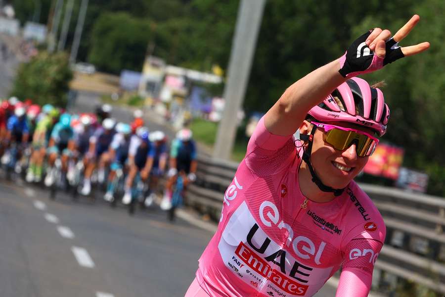 Tadej Pogacar wearing the overall leader's pink jersey gestures a victory sign