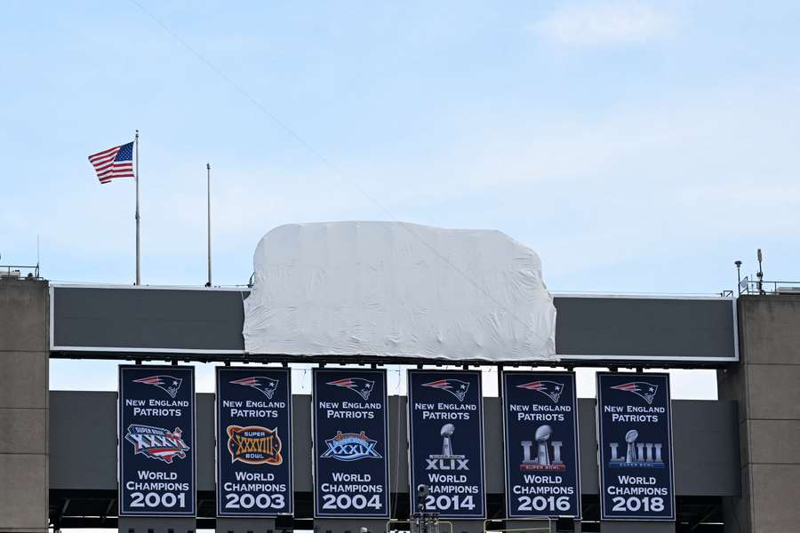 As bandeiras de campeão do Super Bowl exibidas pelos Patriots e o tampado letreiro da Gillette