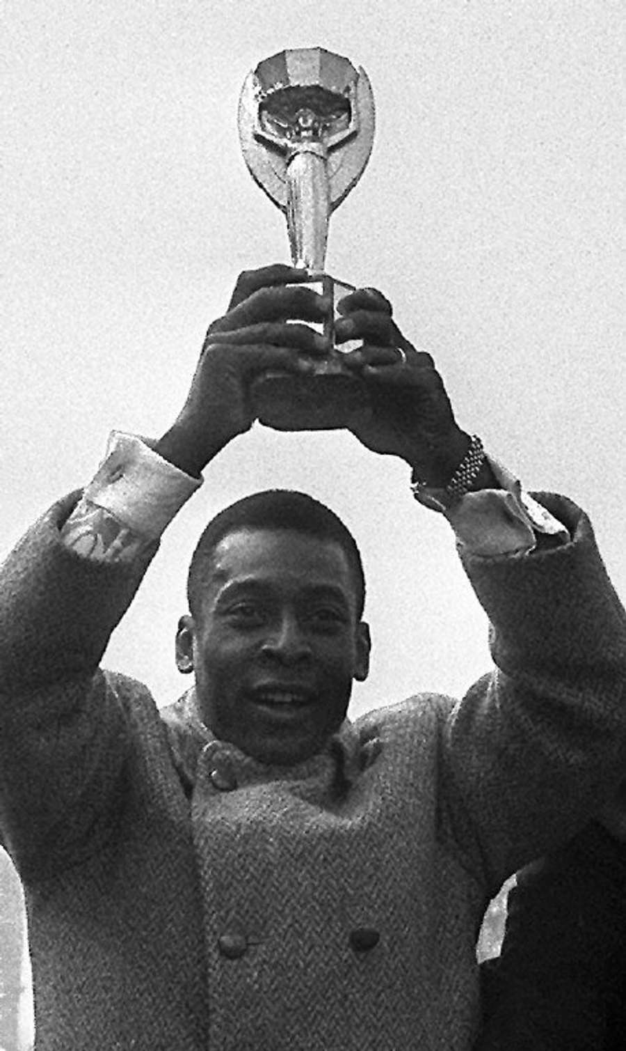 In this file photo taken on March 30, 1971 Brazilian forward Pele shows the Jules Rimet Cup to fans, as he parades down the Champs-Elysees in Paris