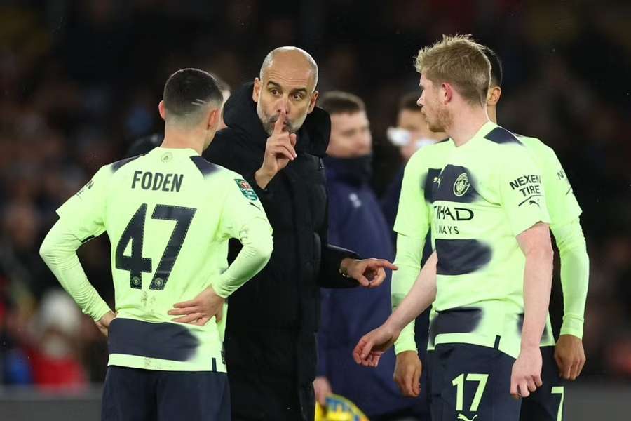 Manchester City manager Pep Guardiola gives instructions to Kevin De Bruyne and Phil Foden