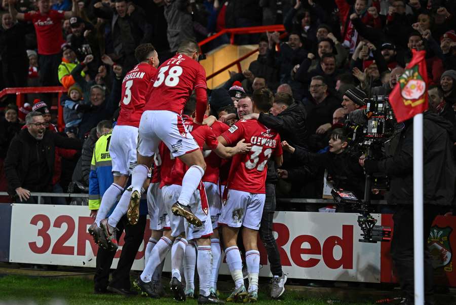 Wrexham's Irish midfielder Thomas O'Connor is mobbed by teammates after scoring the team's second goal