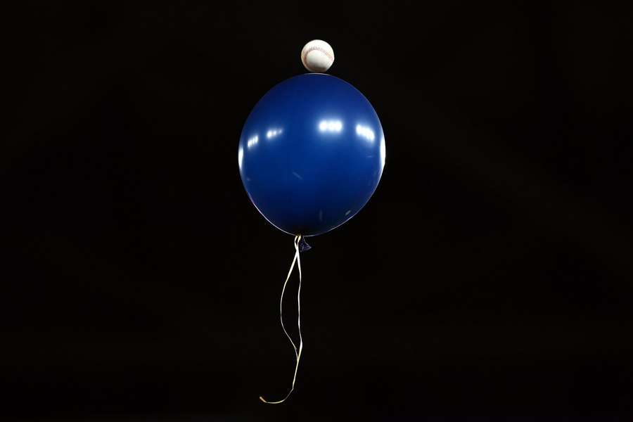 Jogador dos Los Angeles Dodgers lança bola contra um balão Jogador dos Los Angeles Dodgers lança bola contra um balão