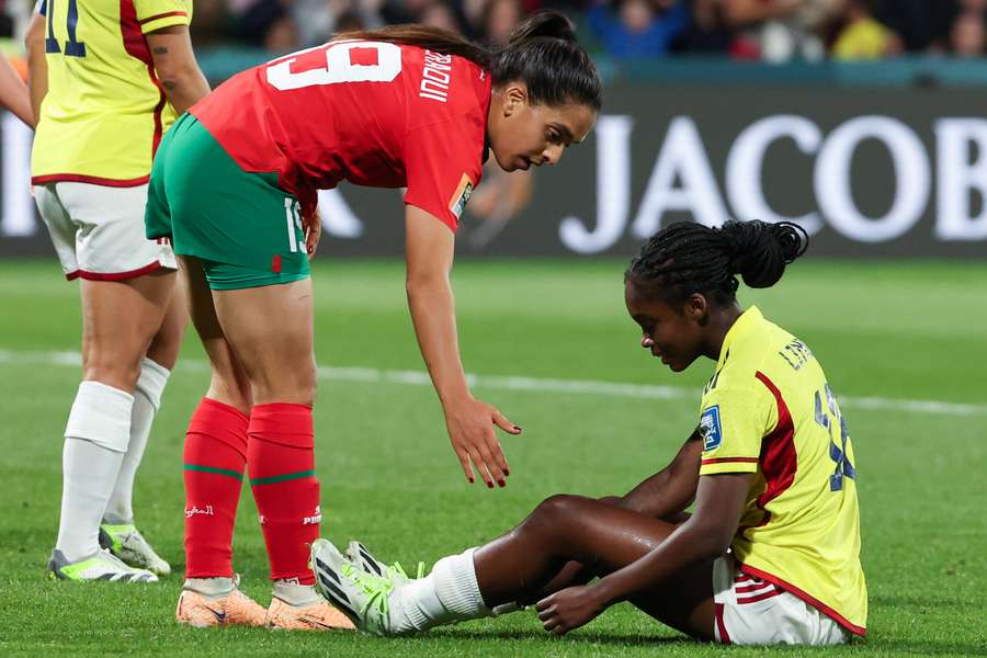 Morocco's forward #19 Sakina Diki (L) helps Colombia's forward #18 Linda Caicedo up after a challenge