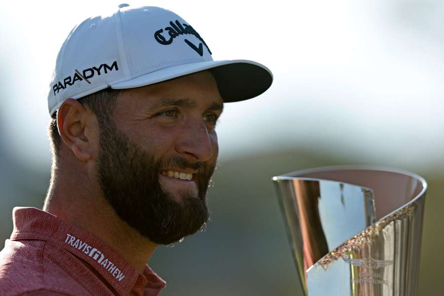 Jon Rahm celebrates with the trophy on the 18th green after winning The Genesis Invitational