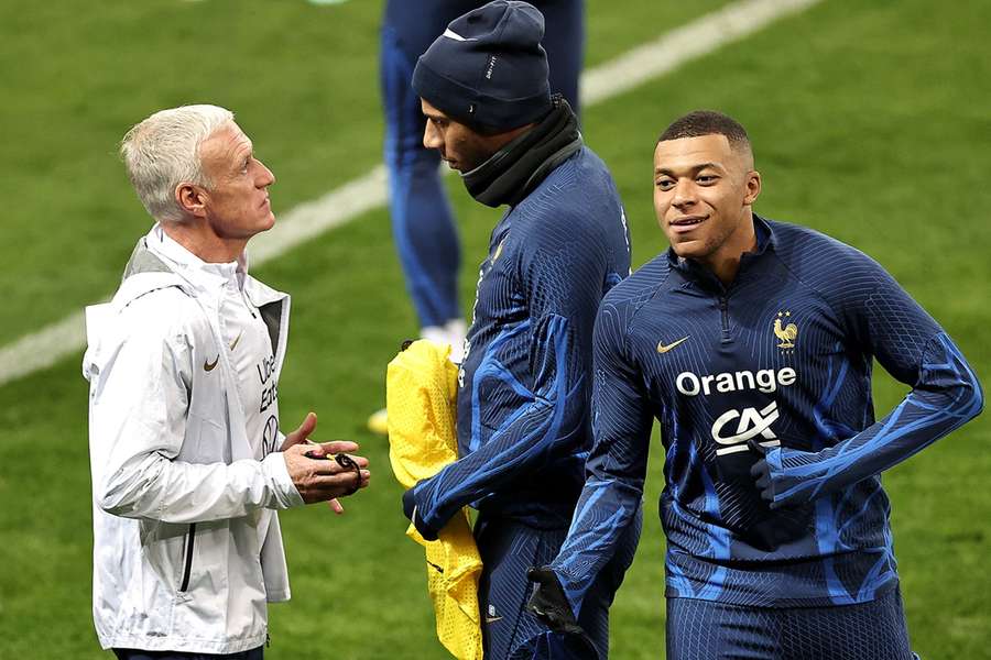 Didier Deschamps praat met Jean Clair Todibo terwijl Kylian Mbappé langsloopt op een training in 2023