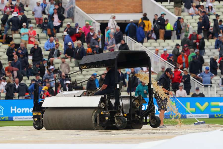 Groundstaff work to clear the water as rain stops play on day three of the first Ashes cricket Test match between England and Australia at Edgbaston