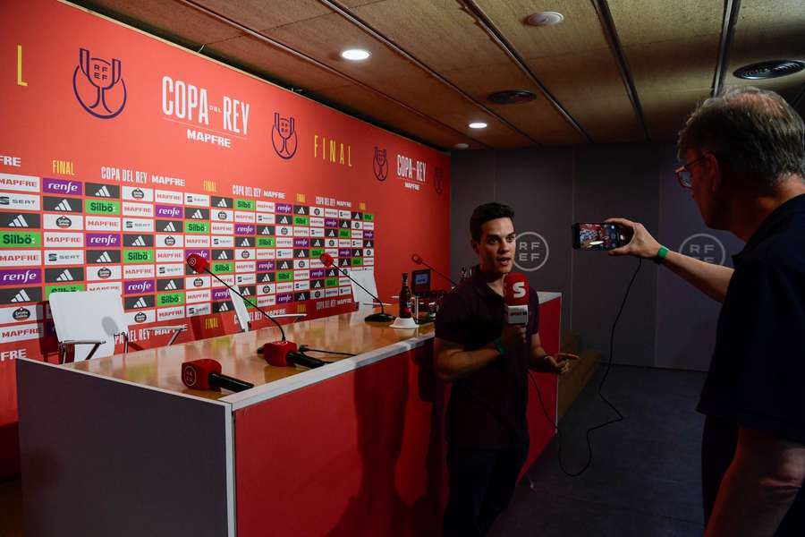 A reporter stands in front of an empty tribune where Carlo Ancelotti was due to give a press conference
