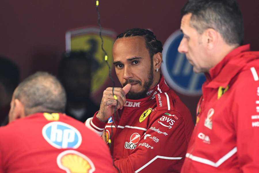 Ferrari's Lewis Hamilton waits with team members as they prepare his car ahead of the Chinese Grand Prix