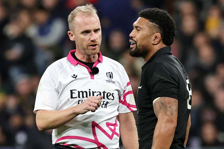Referee Wayne Barnes talks to Aaron Smith of New Zealand after teammate, Sam Cane (not pictured) was shown a red card during the Rugby World Cup final