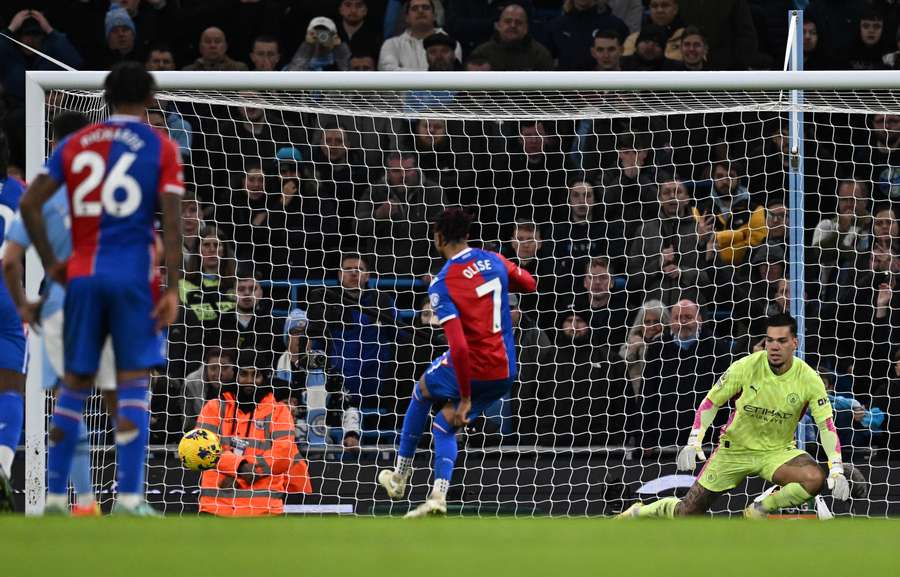 El portero brasileño del Manchester City #31 Ederson (D) observa cómo el centrocampista francés del Crystal Palace #07 Michael Olise lanza desde el punto de penalti