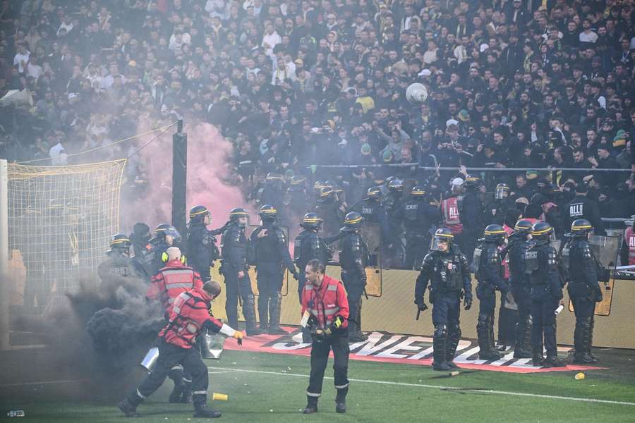 Anti-riot police officers secure the pitch after it was invaded by Nantes' supporters
