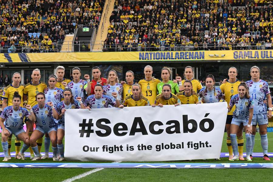 The Spanish and the Swedish team pose with a banner reading "it's over, our fight is the global fight" ahead of their match