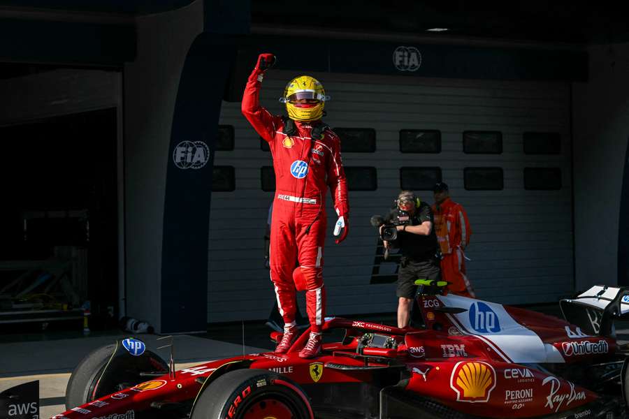 Lewis Hamilton stands on top of his Ferrari