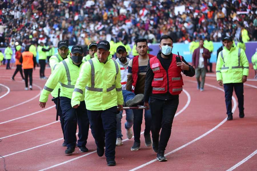 Oficiais médicos auxiliam uma das vítimas de tumulto antes da final da Copa do Golfo