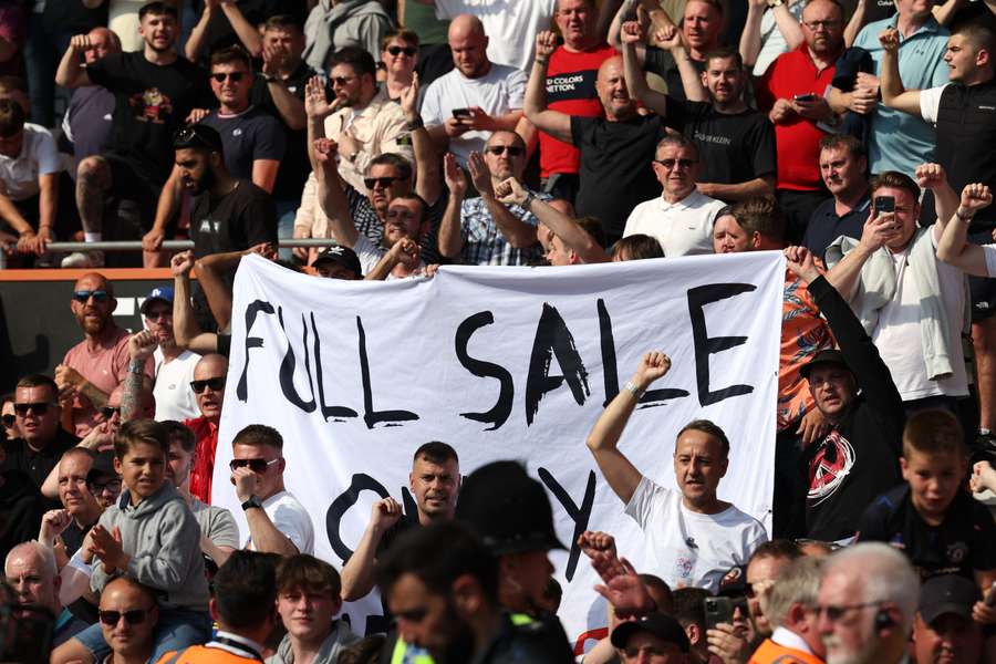 Manchester United fans hold a banner in reference to the club's sale by the Glazer family