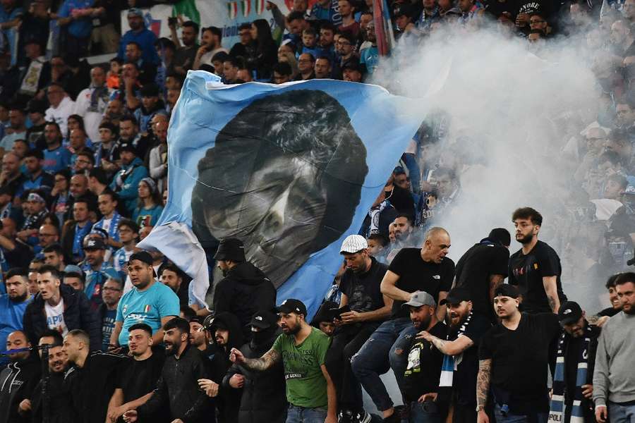 Torcedores do Napoli com uma bandeira de Diego Maradona durante a partida contra a Udinese