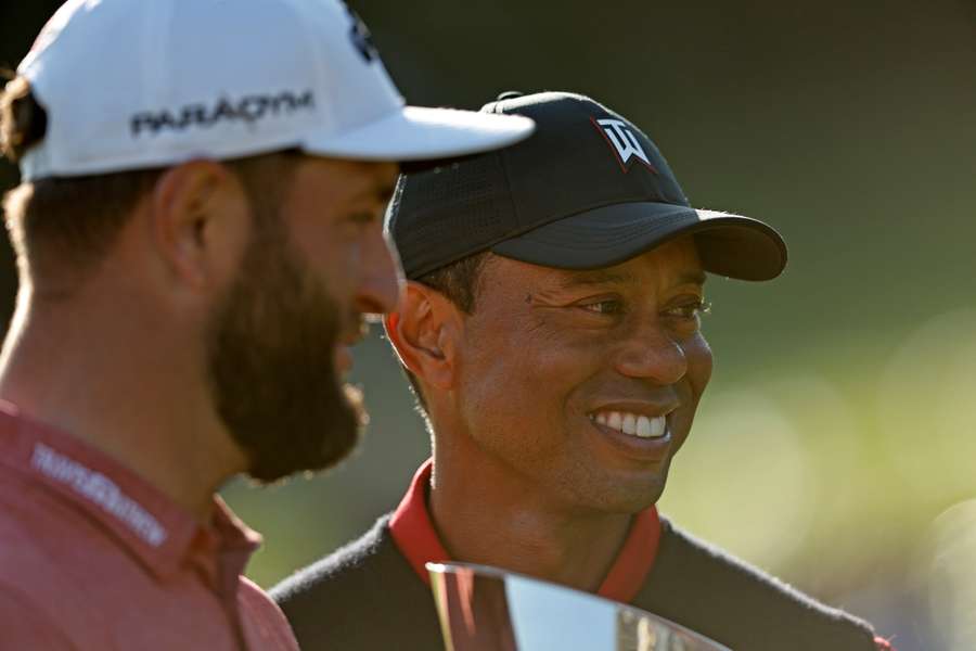 The Genesis Invitational host, Tiger Woods of the United States, presents the trophy to Jon Rahm of Spain