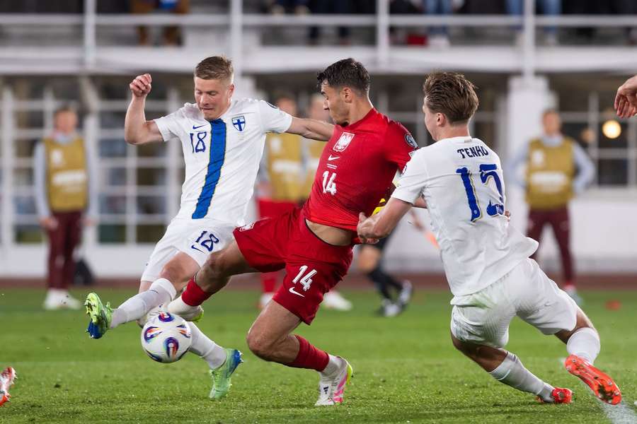 Jakub Kiwior strzela gola dla Polski, obok Miro Tenho i Robin Lod.