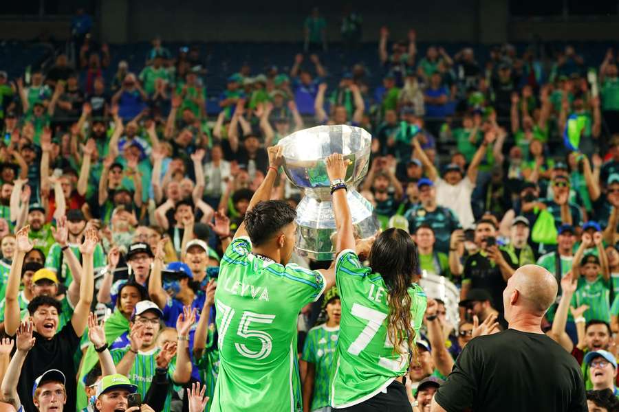 Seattle Sounders players lift the trophy infront of their supporters
