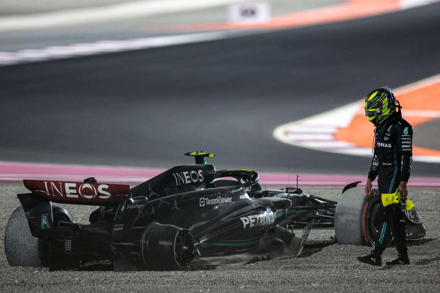 Mercedes' British driver Lewis Hamilton stands next to his damaged car after crashing out
