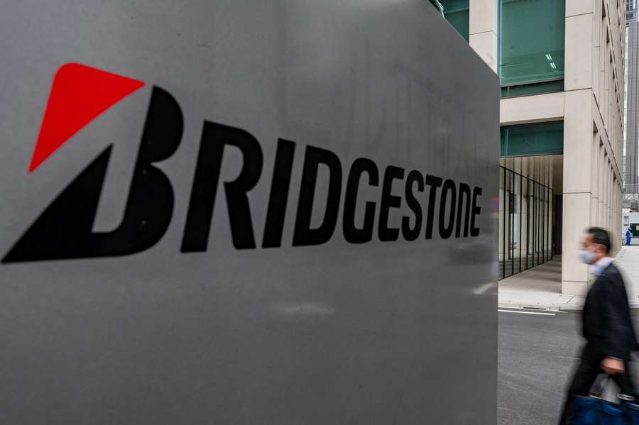 A man walks past the Bridgestone logo near the entrance of Bridgestone Tire Japan Headquarters in Tokyo on November 12, 2020