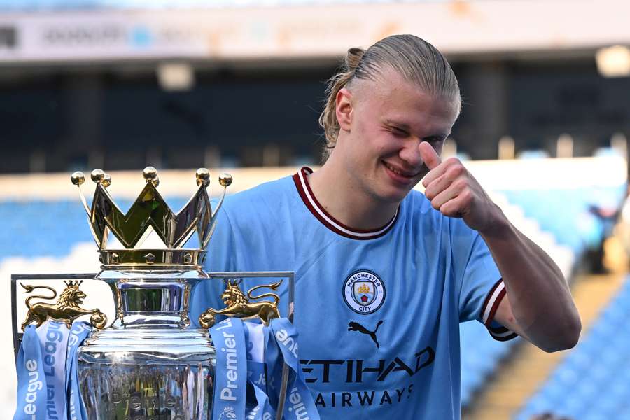 Manchester City's Norwegian striker Erling Haaland poses with the Premier League trophy on the pitch