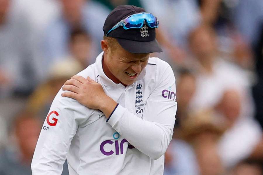 Ollie Pope holds his shoulder after injuring it in the field for England