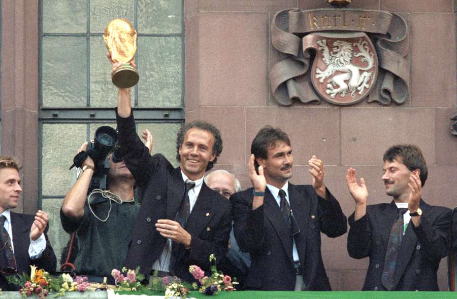 Franz Beckenbauer (L) regge il trofeo della Coppa del Mondo vinta in Italia sul balcone del Römer