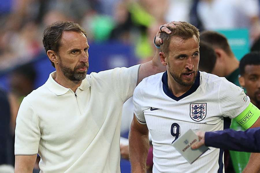 England's forward #09 Harry Kane (R) is checked on by England's head coach Gareth Southgate after falling on the side of the pitch