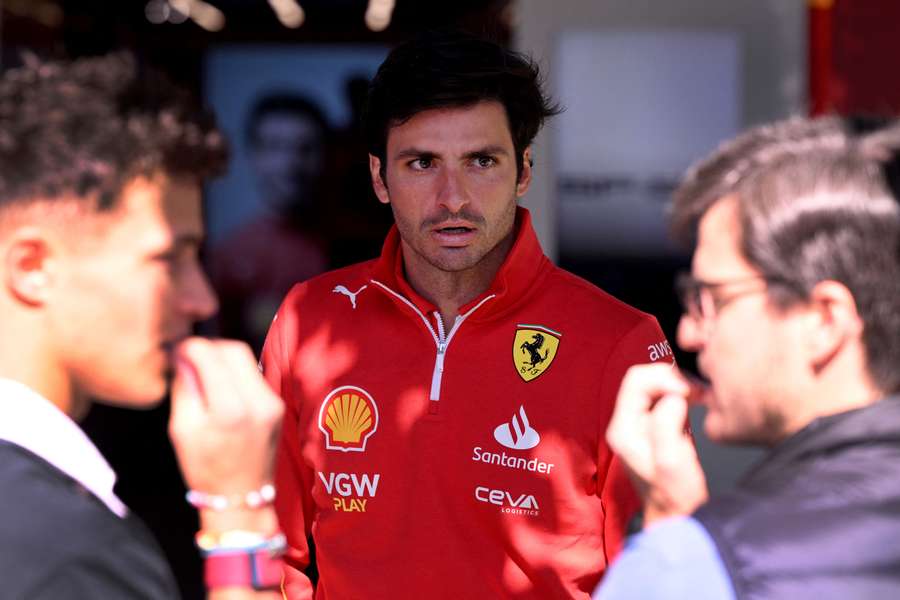 Ferrari Carlos Sainz (C) speaks in the paddock at the Albert Park Circuit as Formula 1 teams prepare ahead of the Australian Grand Prix