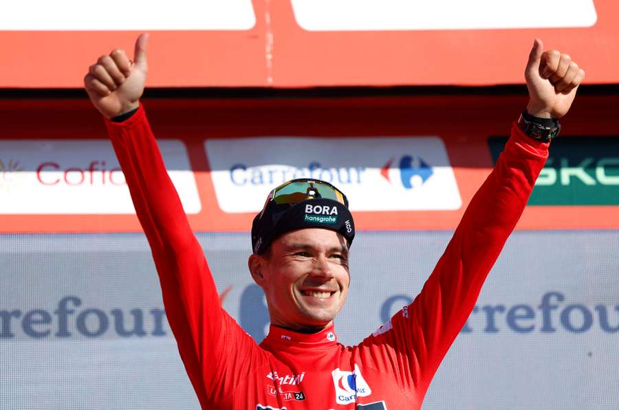 Hansgrohe's Primoz Roglic celebrates on the podium while wearing the red jersey 