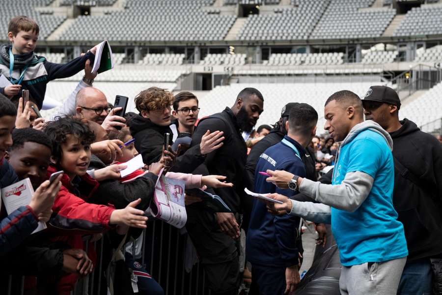 French forward Kylian Mbappe sign autographs after taking part in a football match with children from the 