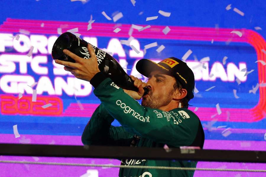 Aston Martin's Fernando Alonso drinks champagne on the podium