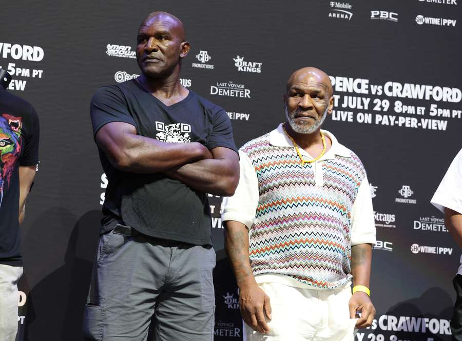 Evander Holyfield (L) and Mike Tyson look on during the weigh-in for Terrence Crawford and Errol Spence Jr.