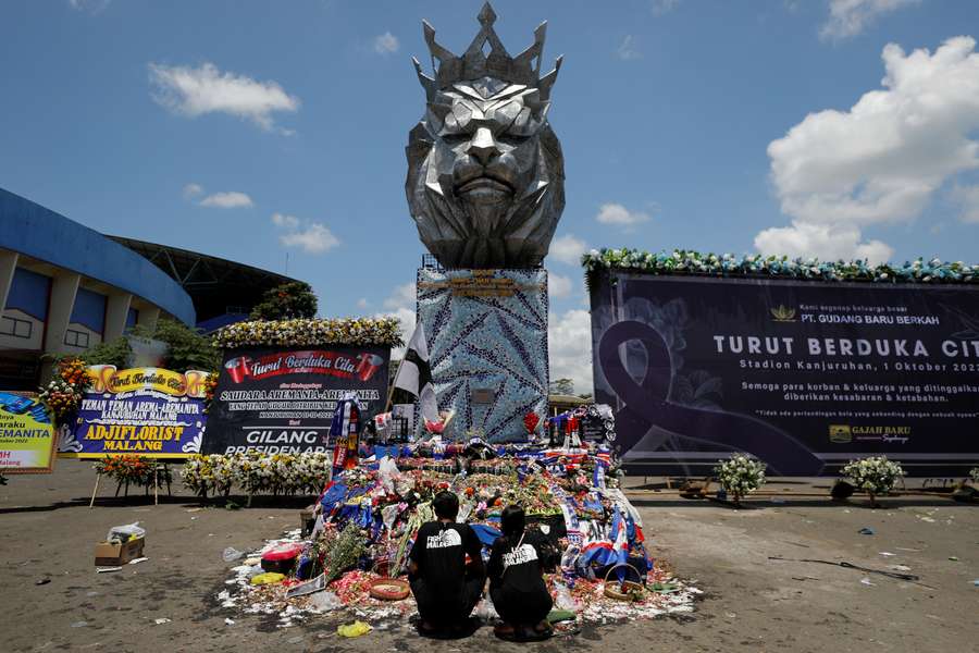 Arema FC supporters pray at a monument as they pay their condolences to the victims of the stampede