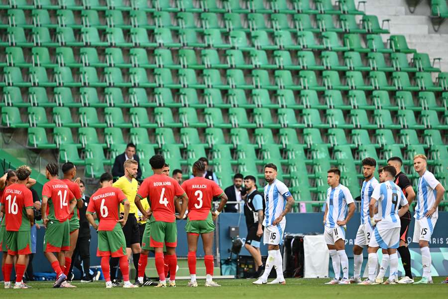 Swedish referee Glenn Nyberg looks on as Argentina's (R) and Morocco's players prepare to start playing again in an emptied stadium