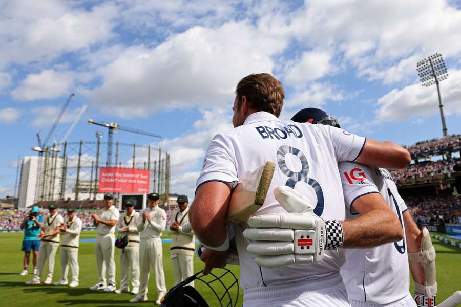 England's Stuart Broad (C), arm in arm with England's James Anderson (R), is given a guard of honour by the Australia players