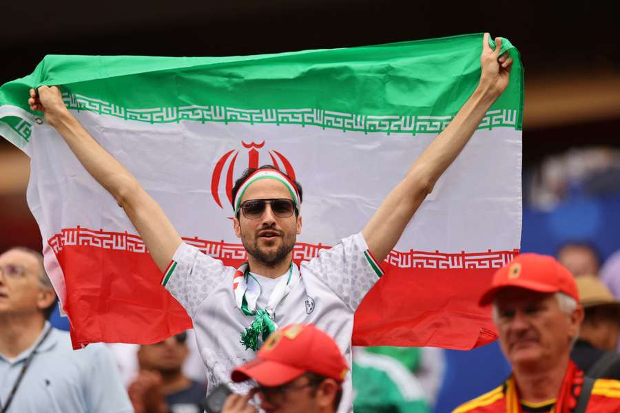 An Iran fan displays their national flag before the match An Iran fan displays their national flag before the match