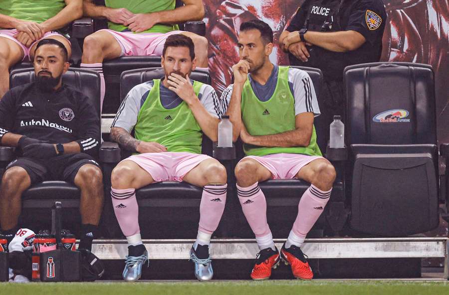 Argentyński napastnik Interu Miami #10 Lionel Messi (C) i hiszpański pomocnik Interu Miami #05 Sergio Busquets (R) siedzą na ławce.