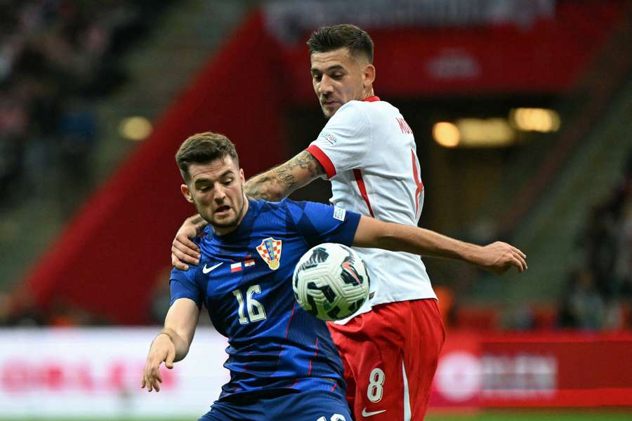 Martin Baturina (Croacia) y Jakub Moder (Polonia) se disputan el balón 