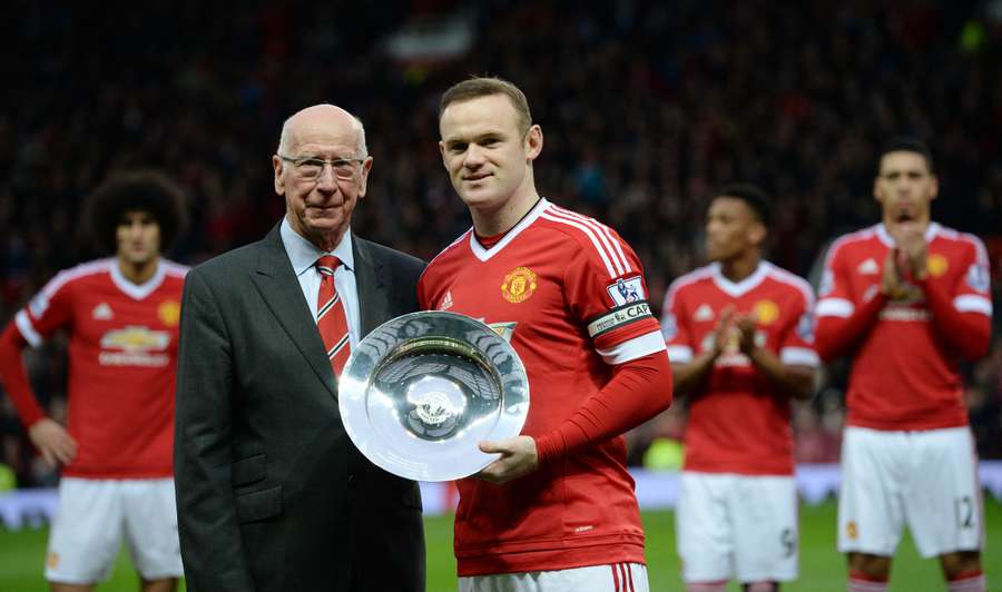 Manchester United's English striker Wayne Rooney receives an award from former Manchester United player Sir Bobby Charlton before playing in his 500th game for his club