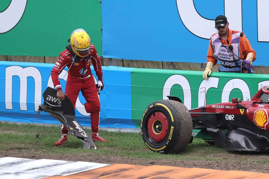 Lewis Hamilton picks up his front wing after crashing around turn three