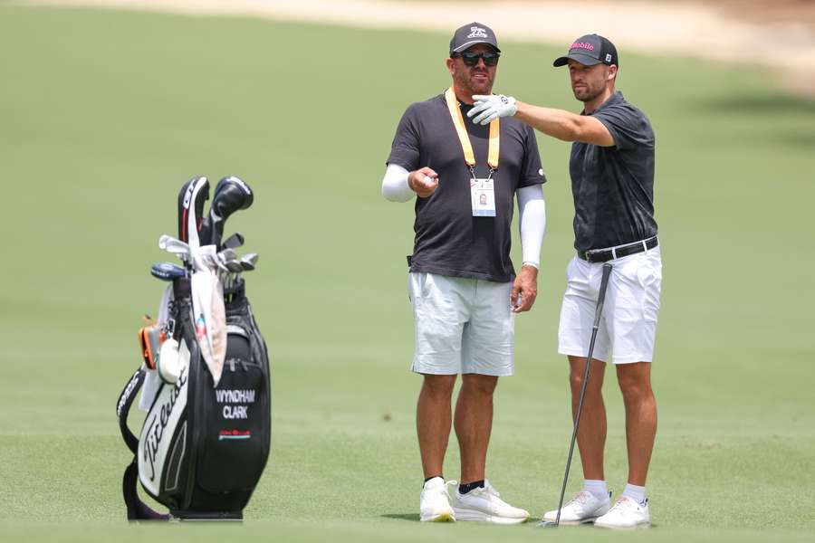 Wyndham Clark of the United States talks with his caddie John Ellis during a practice round