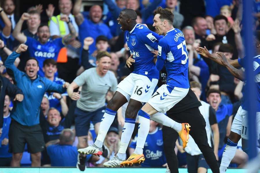 Everton's French midfielder Abdoulaye Doucoure (C) celebrates with teammates after scoring
