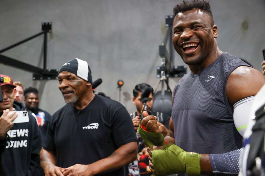 Former US boxer Mike Tyson, left, and Cameroonian-French mixed martial arts star and boxer Francis Ngannou laugh while talking to media 
